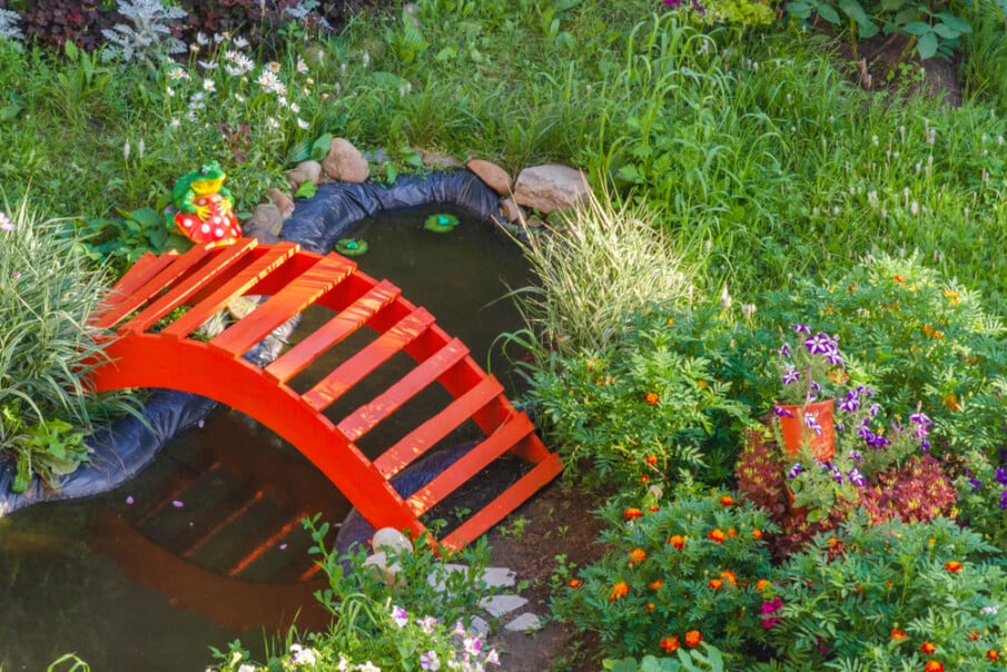 A simple DIY bridge is placed over a small pond