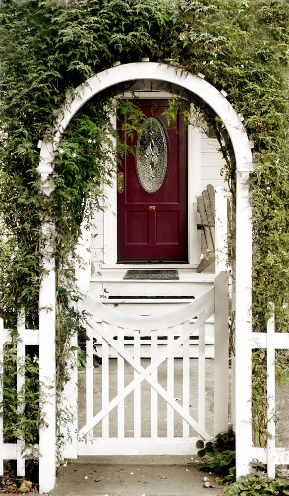 White vinyl arbor gate covered with greenery