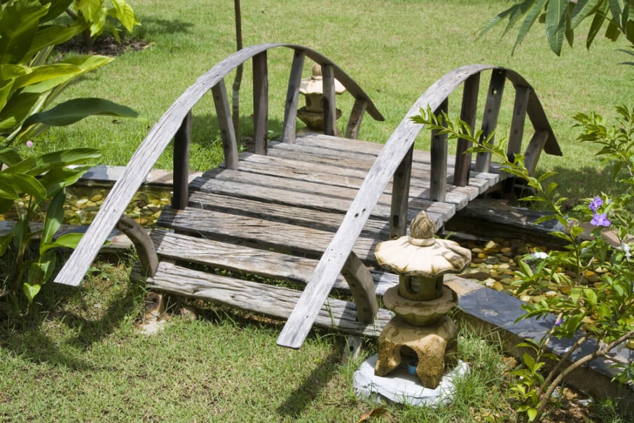 A garden creek bridge with wooden curved handrails