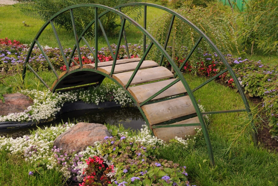 A pond bridge with metal curved handrails